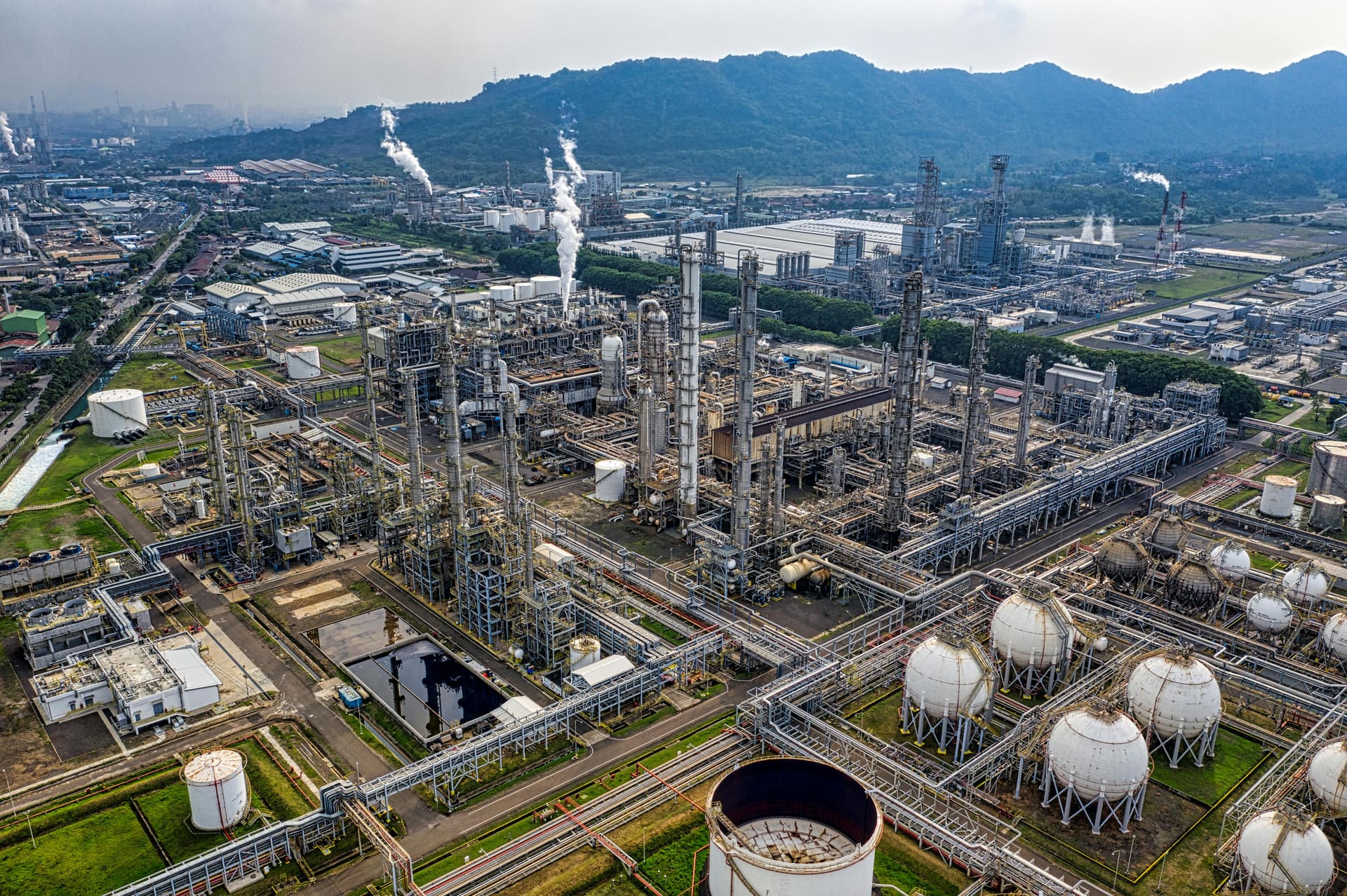 Aerial view of a petroleum refinery and terminal complex with tank farm and processing units.
